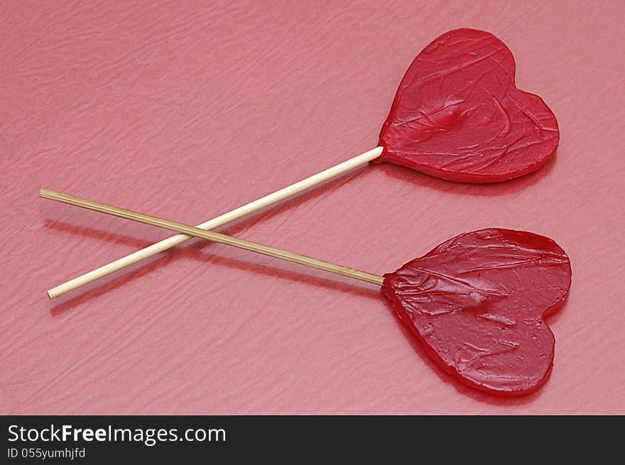 Two heart shape lollipops with a red background