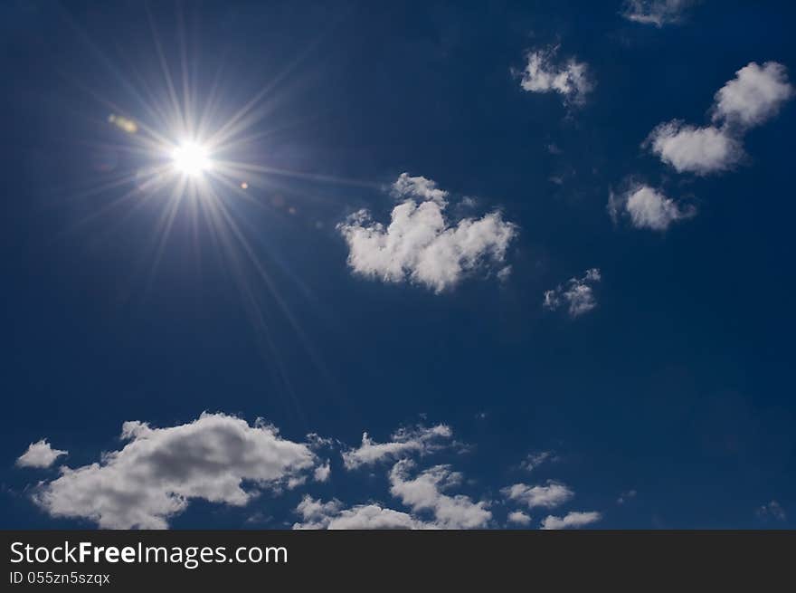 Radiant sun on blue sky with some clouds