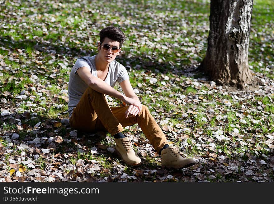 Portrait of a young handsome man, model of fashion, with modern hairstyle in the park. Portrait of a young handsome man, model of fashion, with modern hairstyle in the park