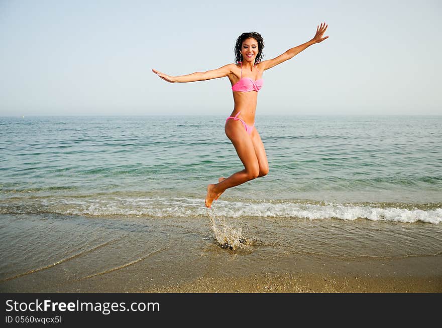 Woman with beautiful body jumping in a tropical beach