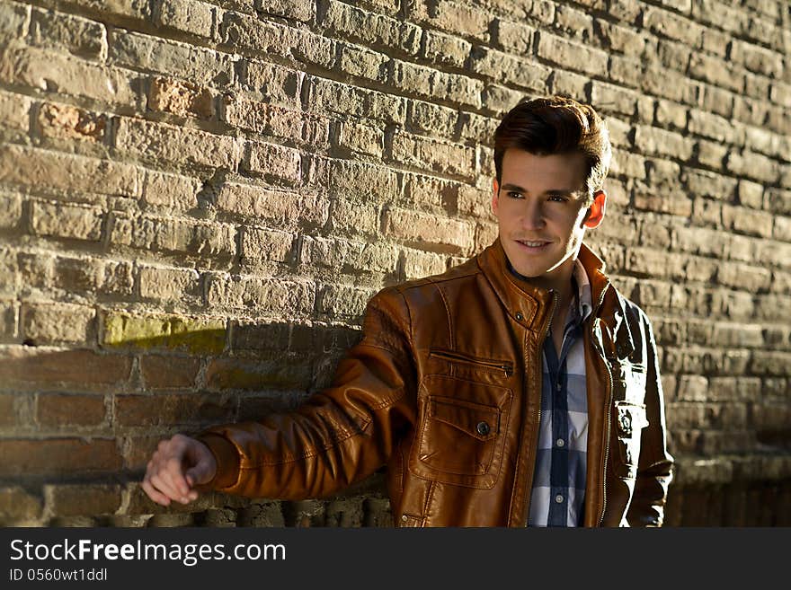 Portrait of handsome man with modern hairstyle smiling in urban background