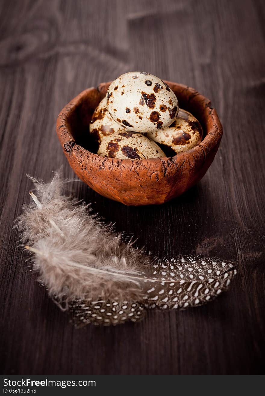 Quail eggs with feathers on a wooden board