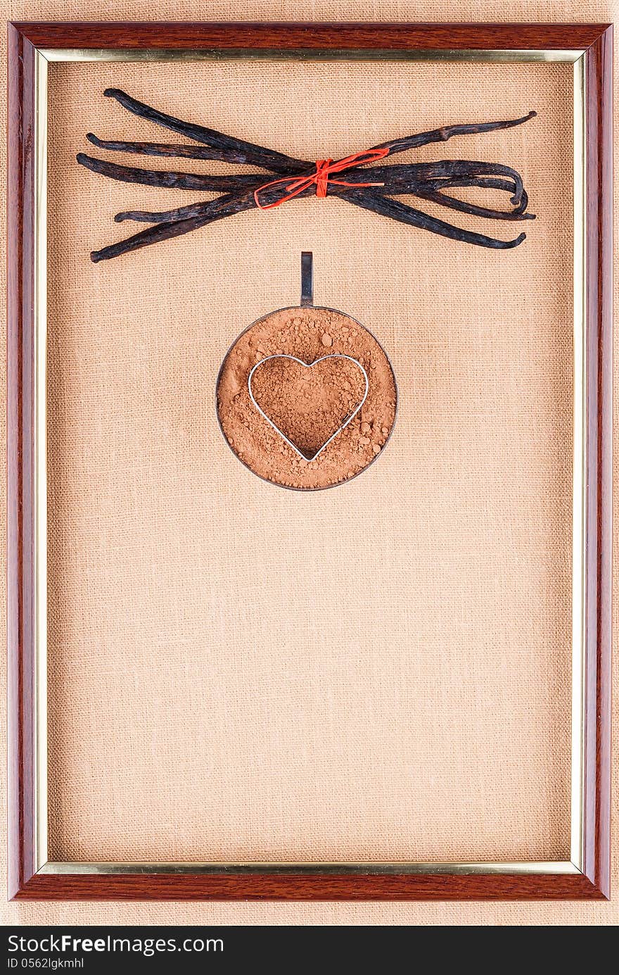 Steel cup cocoa powder with form of heart and vanilla beans bundle tied with red twine in the frame on a linen background. Steel cup cocoa powder with form of heart and vanilla beans bundle tied with red twine in the frame on a linen background