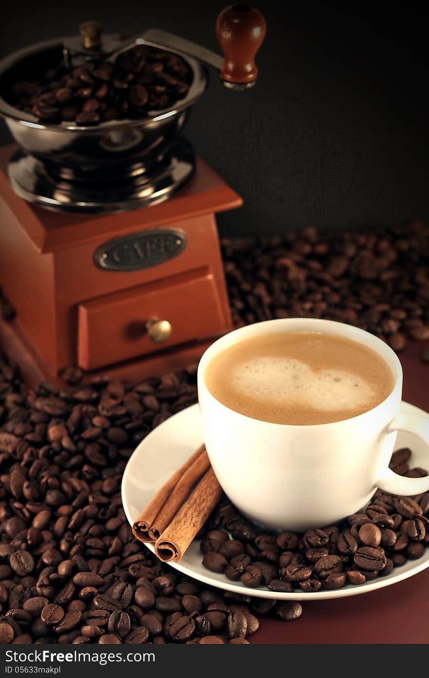 Cup of coffee and coffee mill with cinnamon sticks