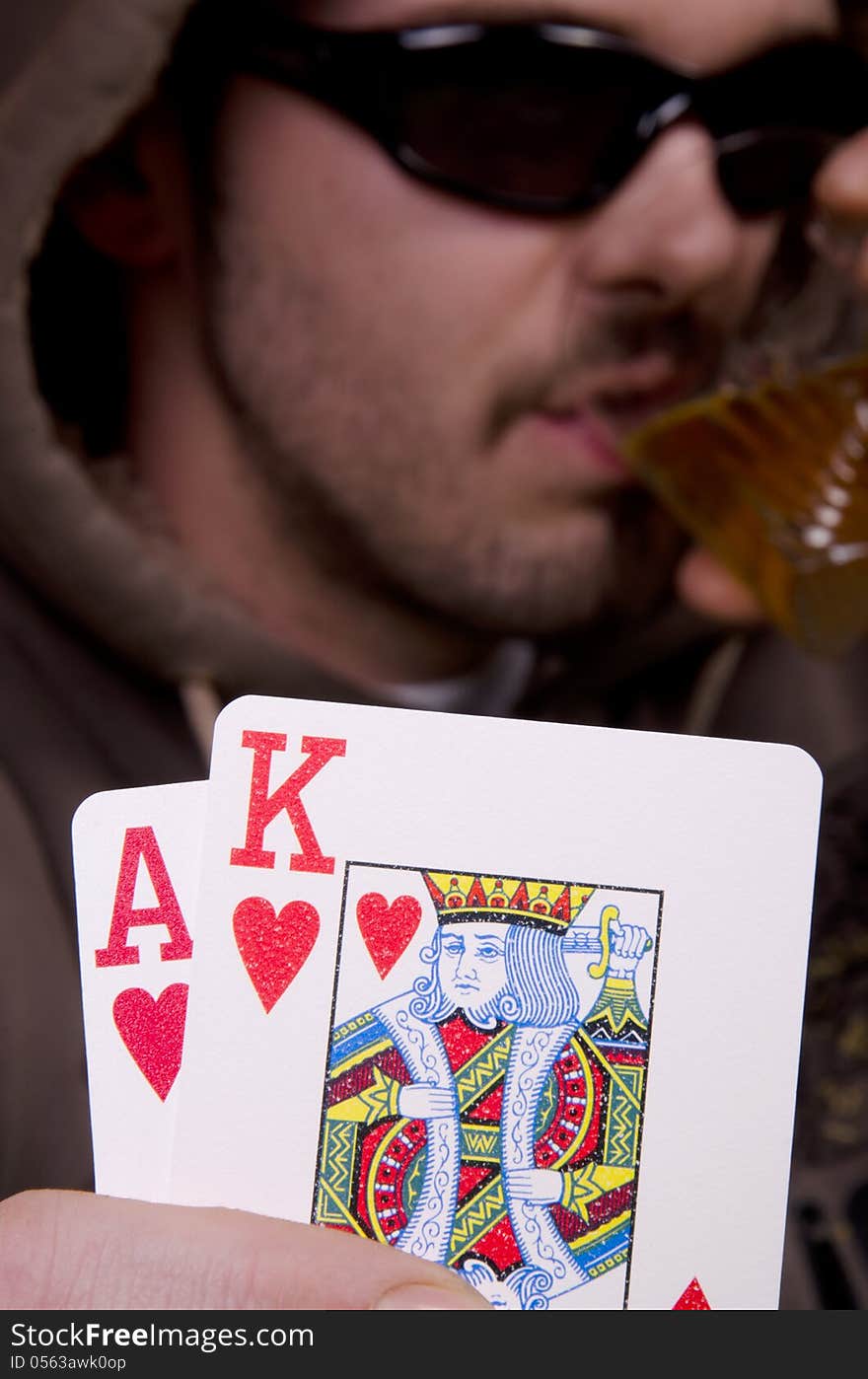 Poker player is drinking and showing his cards. Poker player is drinking and showing his cards.