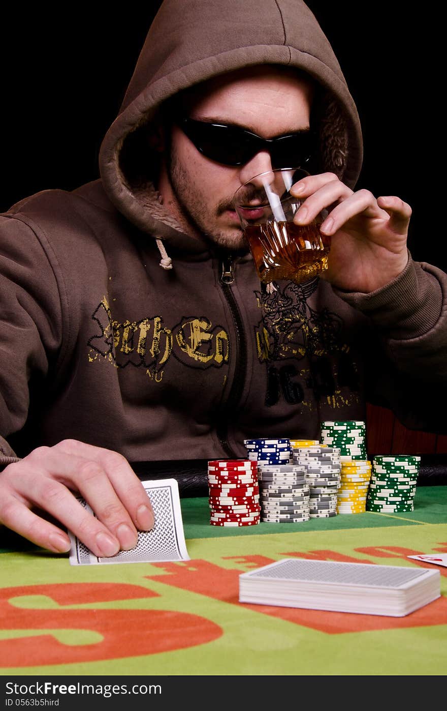 Poker player is drinking and looking his cards. Poker player is drinking and looking his cards.