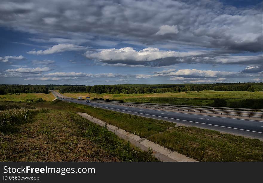 The highway with cars in the summer in a wood environment. The highway with cars in the summer in a wood environment