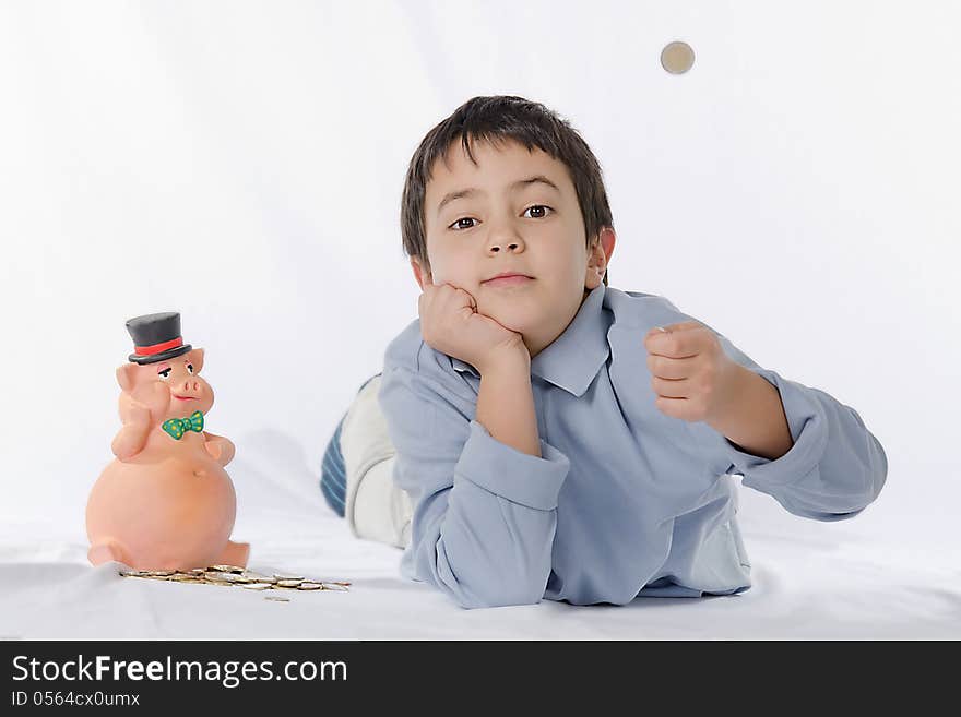 Piggy bank and child on a white background brightly lit. the child throws a coin in the air.