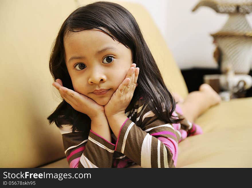 Beautiful young girl look emptily looking at the camera on the couch. Beautiful young girl look emptily looking at the camera on the couch