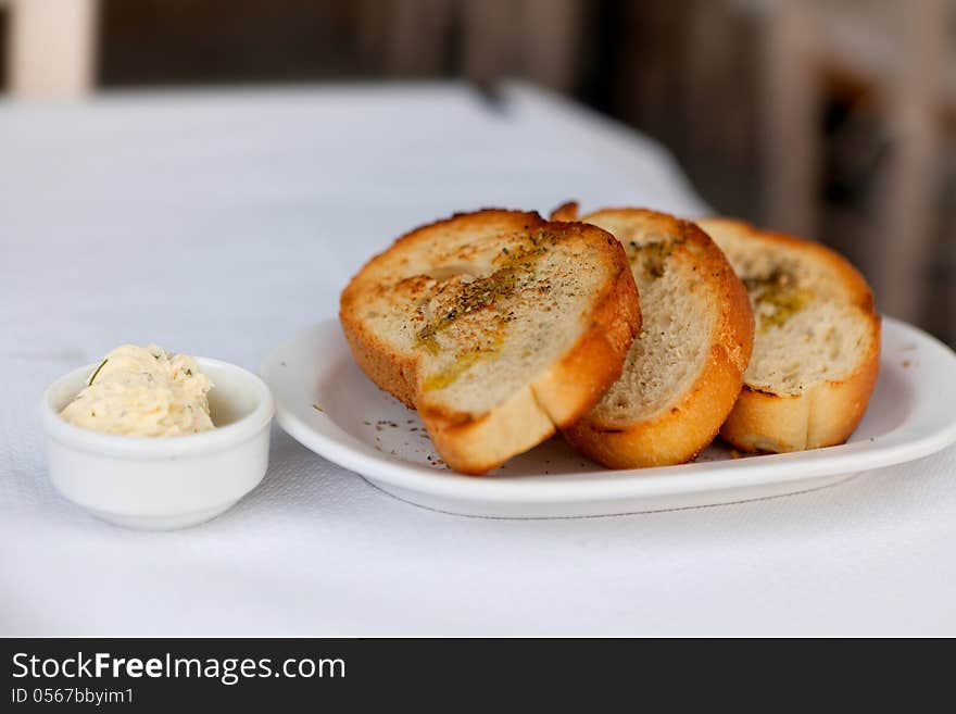 Toasted bread with garlic and spices on a white plate and butter. Toasted bread with garlic and spices on a white plate and butter