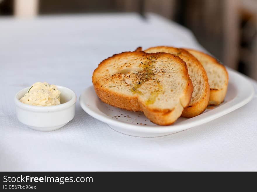 Toasted bread with garlic and spices on a white plate and butter. Toasted bread with garlic and spices on a white plate and butter