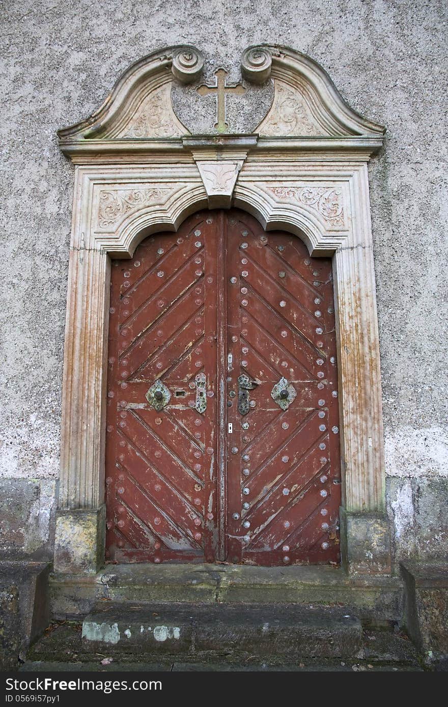 Ornate wooden doors of the church, cross above the door