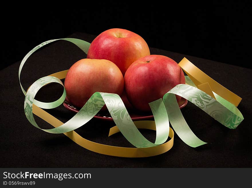 Red apples on a black background with color ribbons. Red apples on a black background with color ribbons