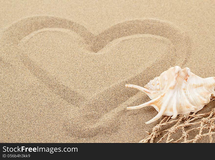 Handwritten heart on yellow soft sand with seashell and shallow focus. Handwritten heart on yellow soft sand with seashell and shallow focus