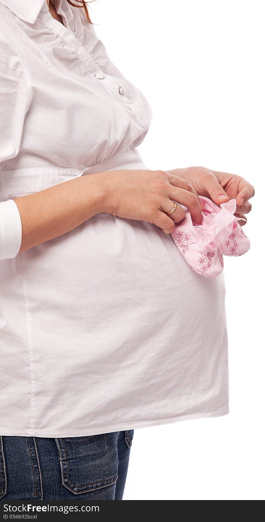 Pregnant woman keeping pink baby-shoes. Close up shot of belly and shoes.