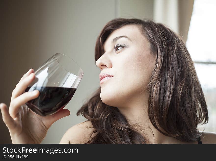 Beautiful young woman with brown hair in lingerie drinking red wine. Beautiful young woman with brown hair in lingerie drinking red wine.