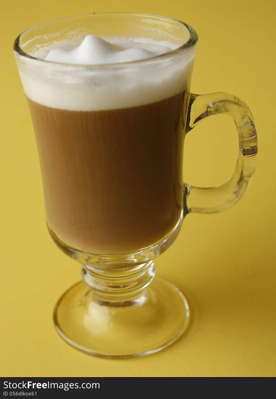 Glass mug of coffee with yellow back round