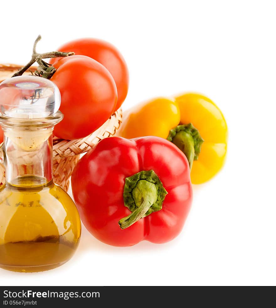 Pepper and a bottle with olive oil on the background of the wattled dish with the vegetables on the white