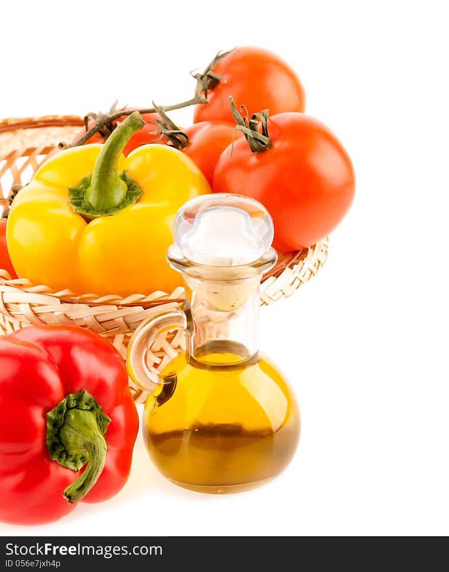 Pepper and a bottle with olive oil on the background of the wattled dish with the vegetables on the white