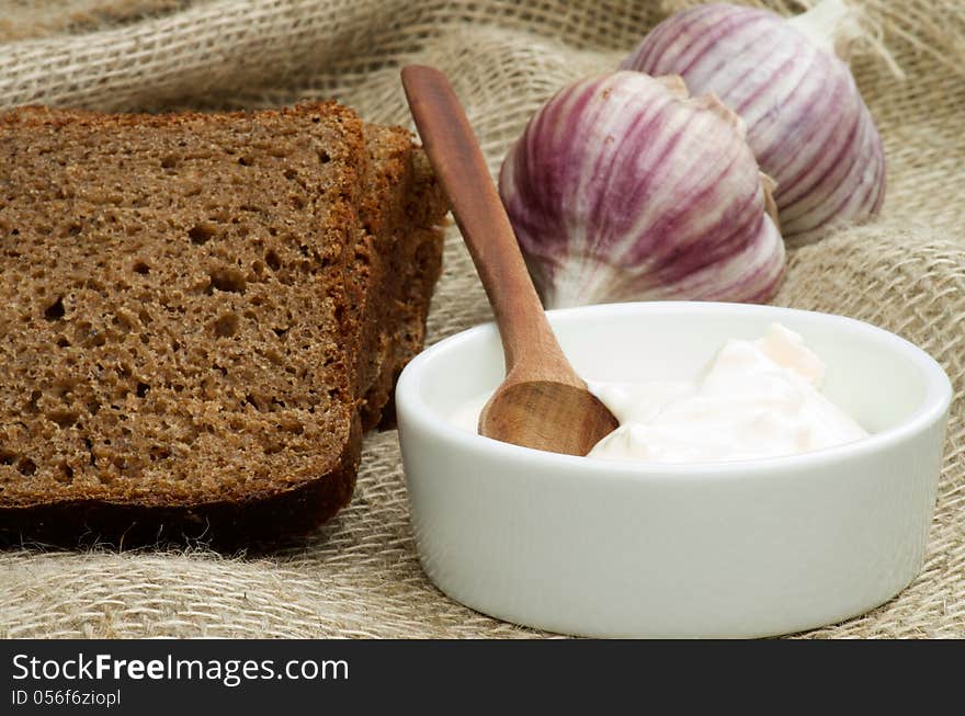 Simple Snack with Sour Cream, Garlic and Brown Bread closeup on Sackcloth background