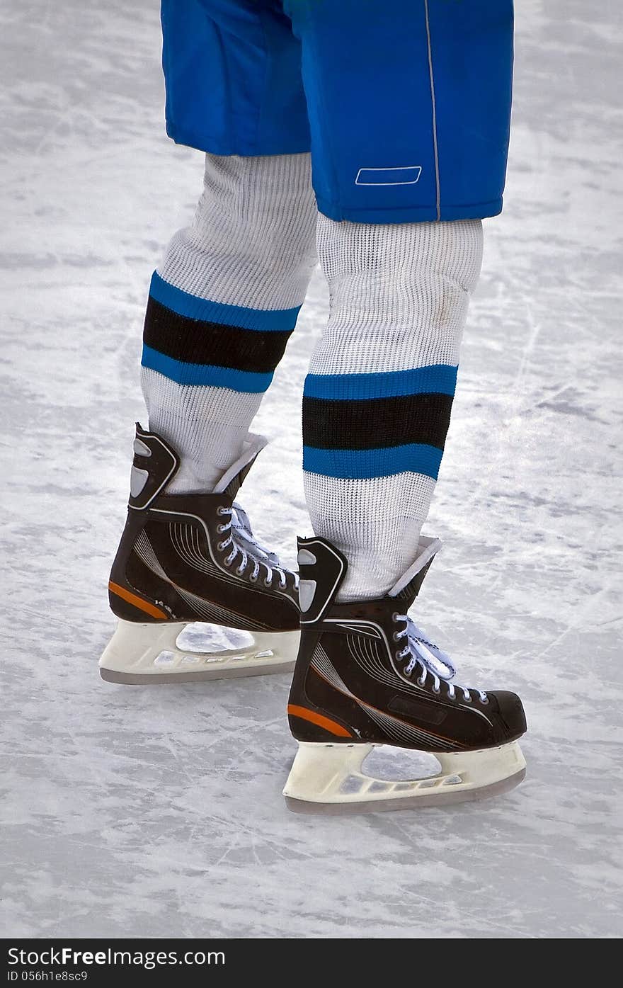 Legs hockey player in uniform standing on skates on ice