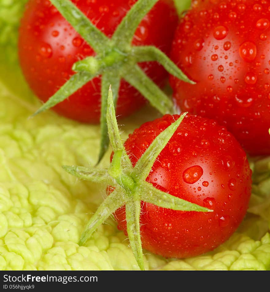 Fresh and wet tomatoes lying on the salad leaves