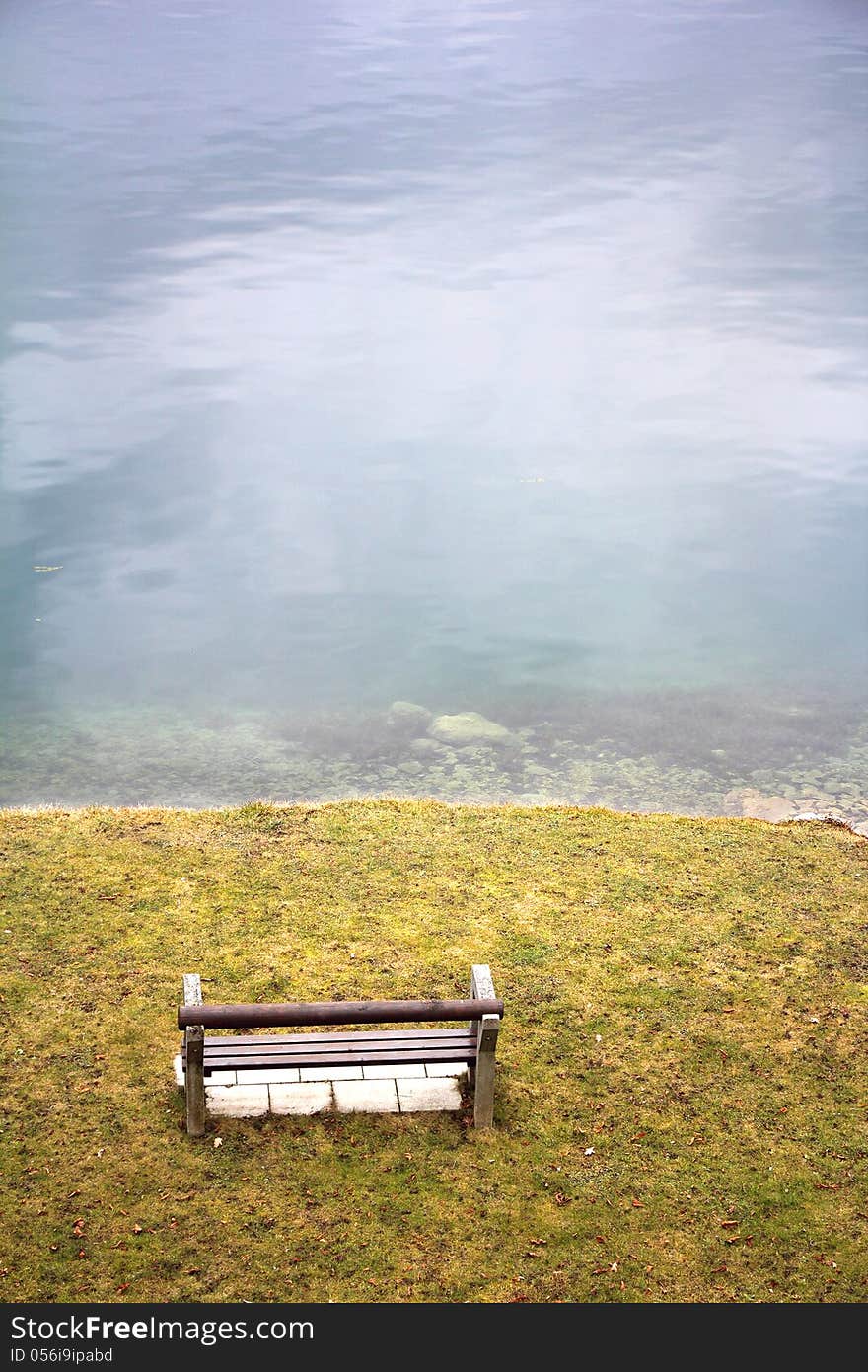 Empty wooden bench on the lake shore