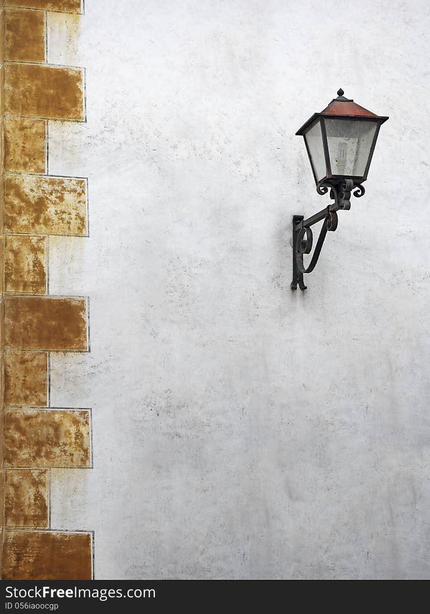 Classic street lantern with wrought iron, on the wall of the old house