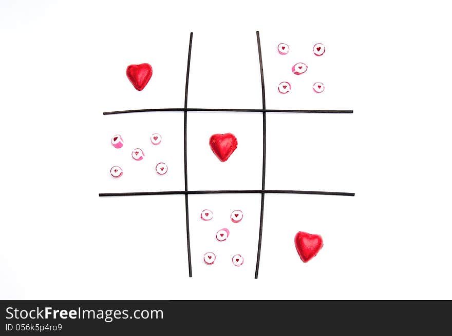 An image representing noughts and crosses with red shaped hearts representing a win and the red candy with hearts in as the opposition. An image representing noughts and crosses with red shaped hearts representing a win and the red candy with hearts in as the opposition