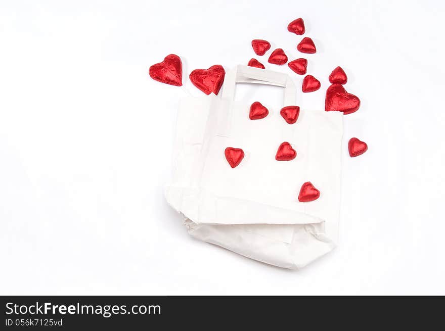 Red hearts scattered on a white paper bag on an isolated white background