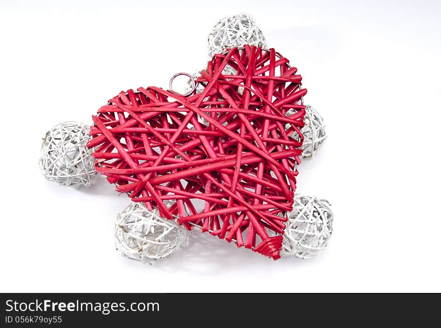 Red wicker heart resting on six small white wicker balls at an angle on white background