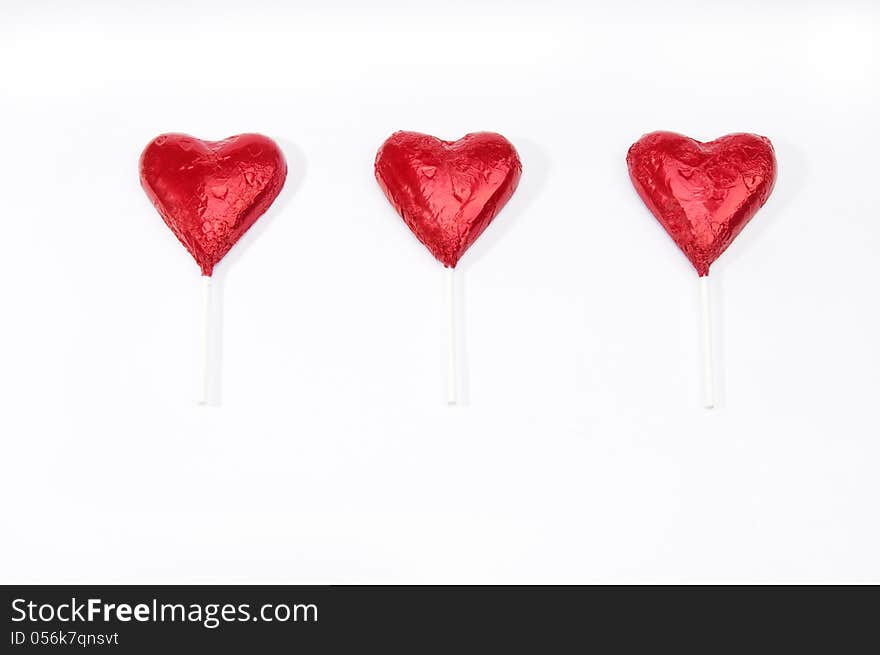 Three red hearts on sticks in a row on an isolated white background