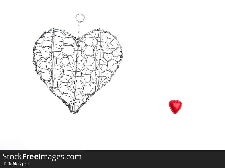 Wire heart shape and a small red hearts on an isolated white background with copy space. Wire heart shape and a small red hearts on an isolated white background with copy space