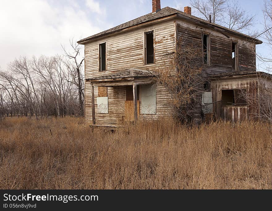 A weathered and worn down old two story house in the country. A weathered and worn down old two story house in the country.