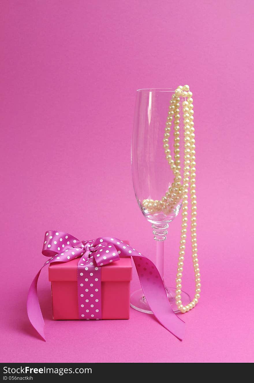 Pretty pink and feminine gift with polka dot pink ribbon and a champagne glass with pearls