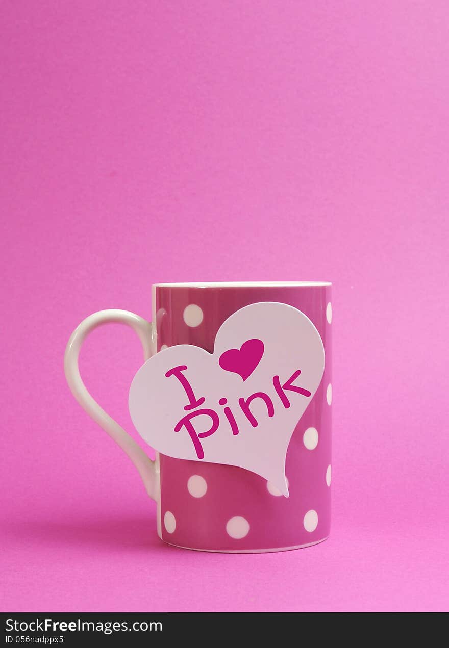 I heart pink message written on a white heart sign tag with pink polka dot coffee mug against a vibrant pink background. I heart pink message written on a white heart sign tag with pink polka dot coffee mug against a vibrant pink background.