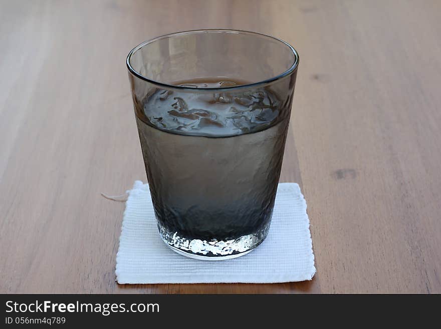 A glass of iced on reflecting table, brown background