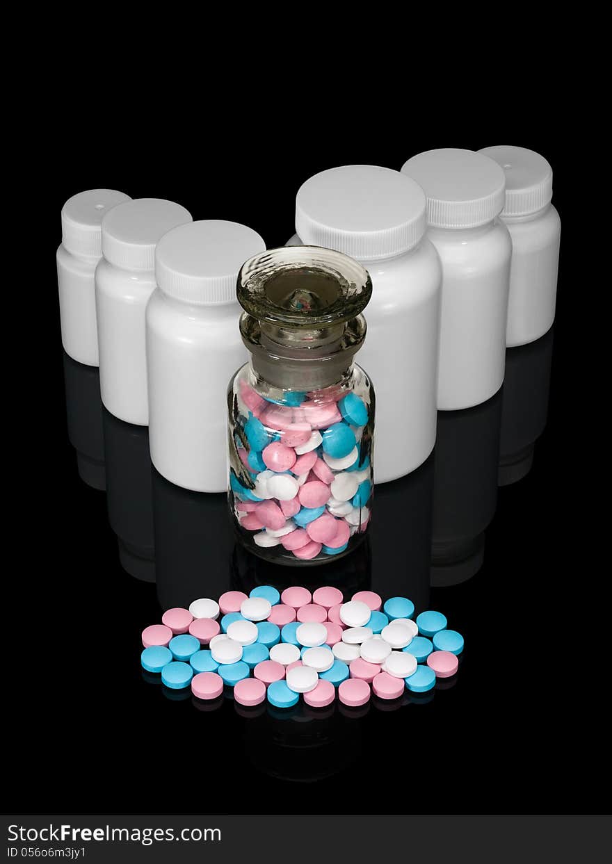 Pills, plastic small bottles and a glass vial on a black background. Pills, plastic small bottles and a glass vial on a black background