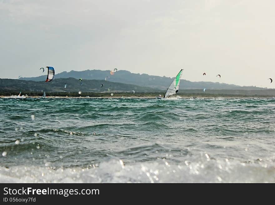 Backlight photo Day of sun wind surfer on spot and in the foreground kite surfing on the beautiful background. Backlight photo Day of sun wind surfer on spot and in the foreground kite surfing on the beautiful background.