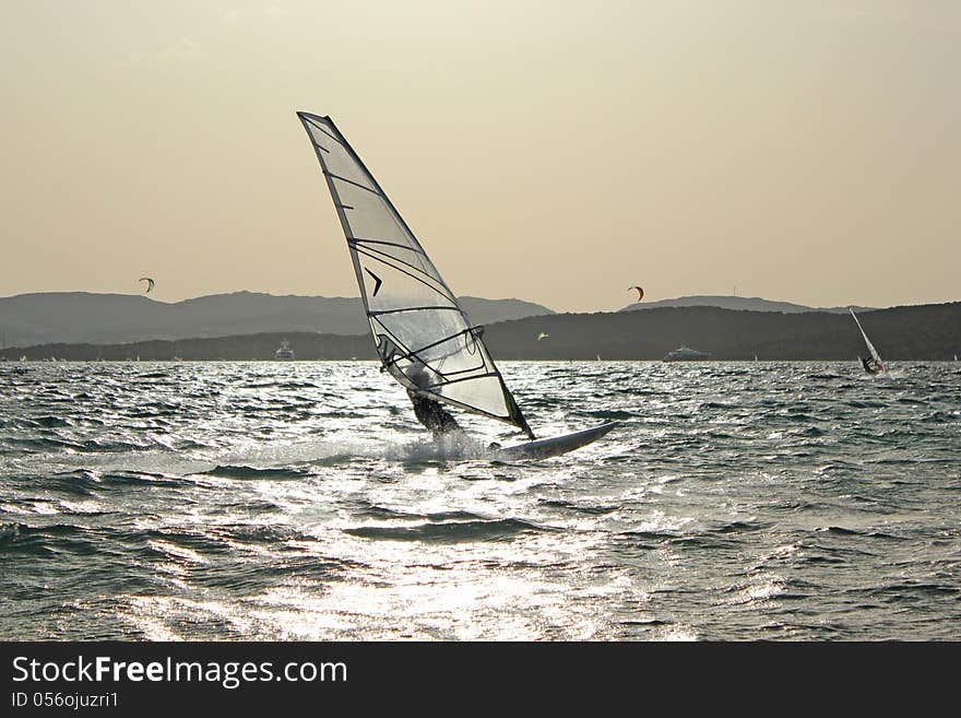 Backlight photo Day of sun wind surfer on spot and in the foreground kite surfing on the beautiful background. Backlight photo Day of sun wind surfer on spot and in the foreground kite surfing on the beautiful background.