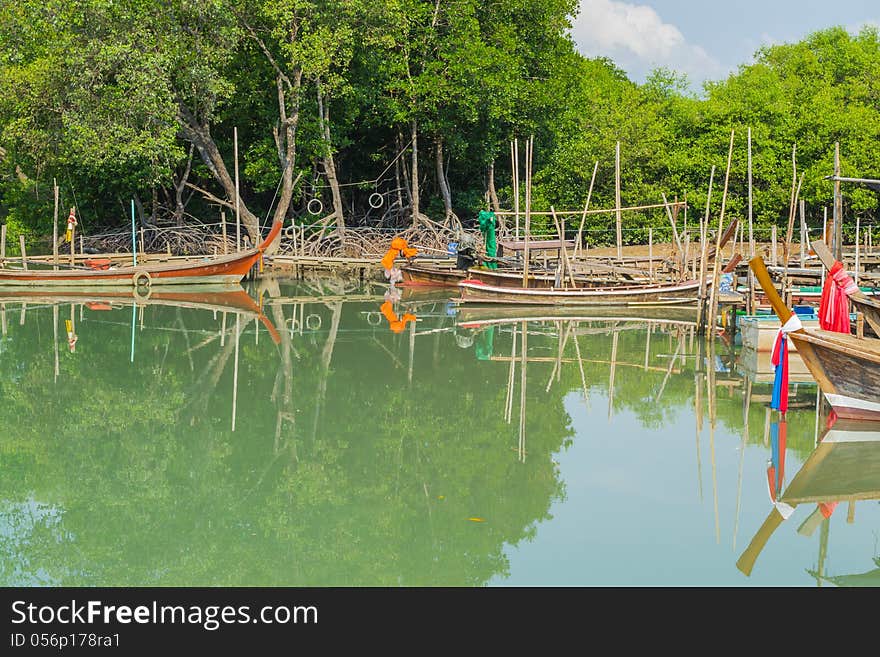 Long tail boats are anchor at the pier among mangrove forest