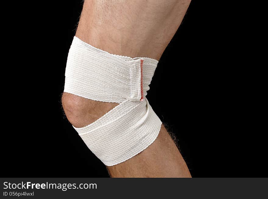 Closeup of male athlete with leg bandaged in sports wrap on black background