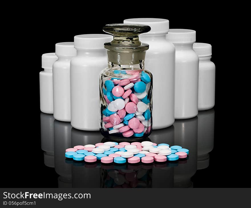 Pills, plastic small bottles and a glass vial on a black background. Pills, plastic small bottles and a glass vial on a black background