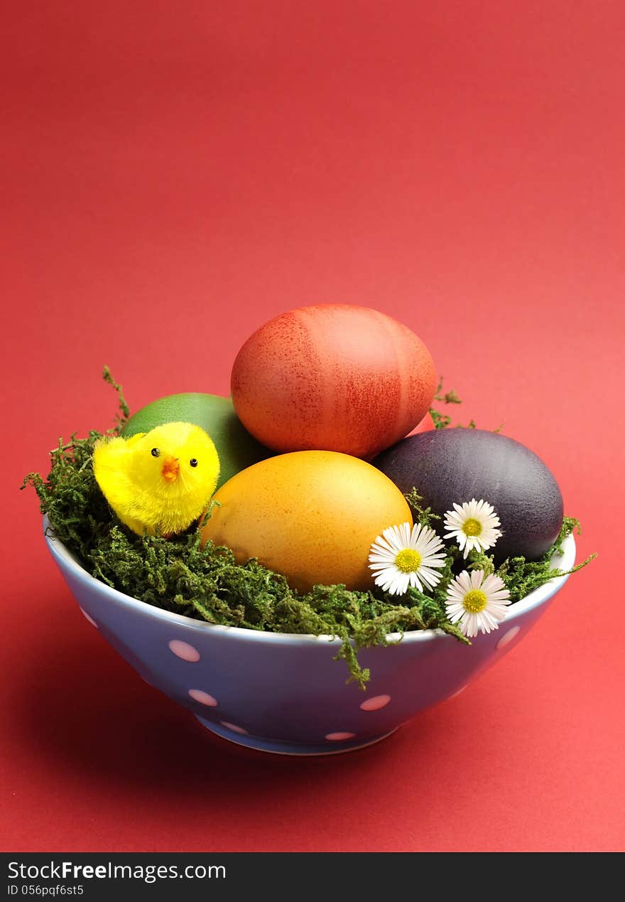 Bright and cheerful Happy Easter still life with rainbow color eggs in orange polka dot bowl against a red background. Bright and cheerful Happy Easter still life with rainbow color eggs in orange polka dot bowl against a red background.