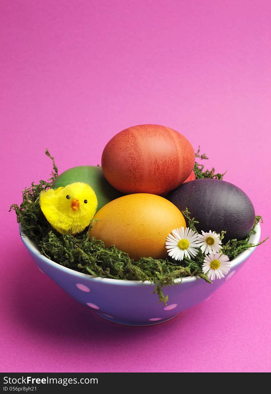 Bright and cheerful Happy Easter still life with rainbow color eggs in orange polka dot bowl against a pink background. Bright and cheerful Happy Easter still life with rainbow color eggs in orange polka dot bowl against a pink background.