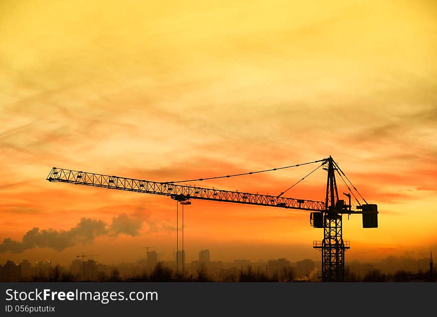 Building crane on background the yellow sky at sunrise. Is view from the heights. Building crane on background the yellow sky at sunrise. Is view from the heights.