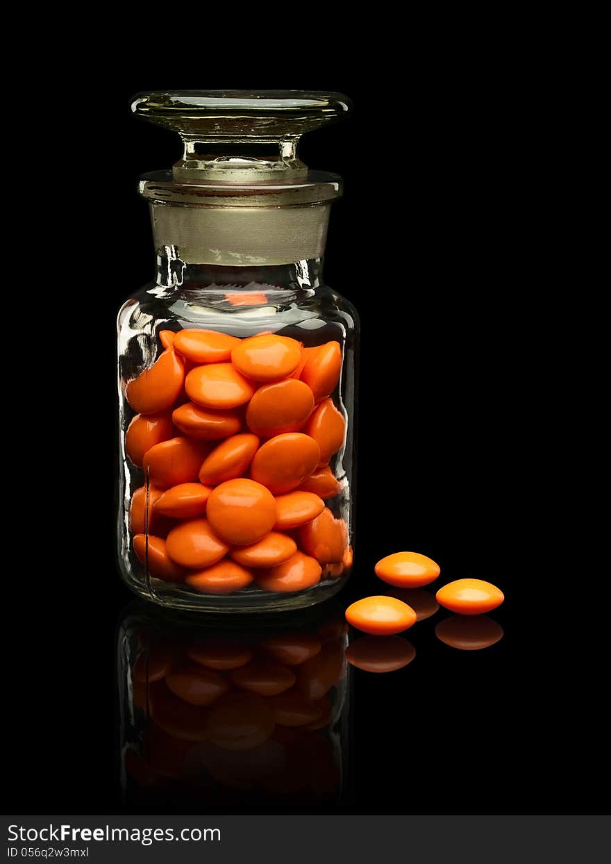 Glass Vial With A Glass Cover And Pills Of Orange Colors.