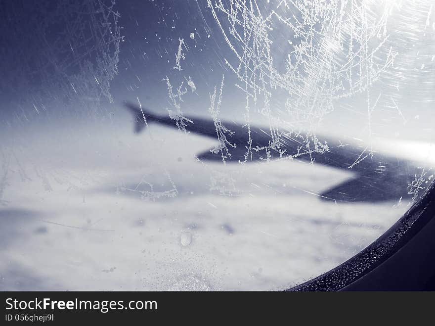 Frosty patterns at a plane window over clouds