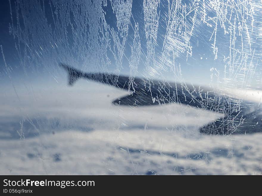 Frosty patterns at a plane window at height over clouds. Frosty patterns at a plane window at height over clouds