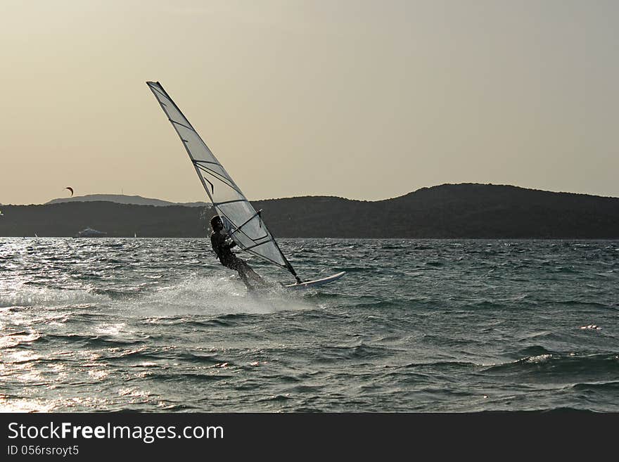 Backlight photo Day of sun wind surfer on spot and in the foreground kite surfing on the beautiful background. Backlight photo Day of sun wind surfer on spot and in the foreground kite surfing on the beautiful background.